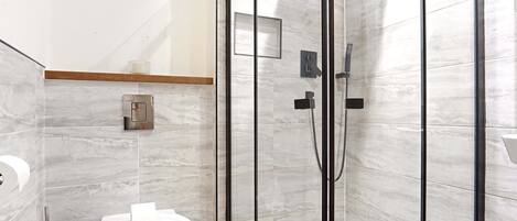 Un baño moderno con inodoro, cabina de ducha y un perchero para toallas.