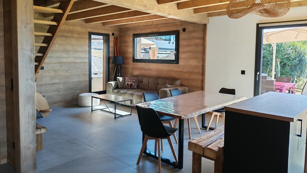 A modern interior with a wooden ceiling, a sofa, a dining table, and a staircase.