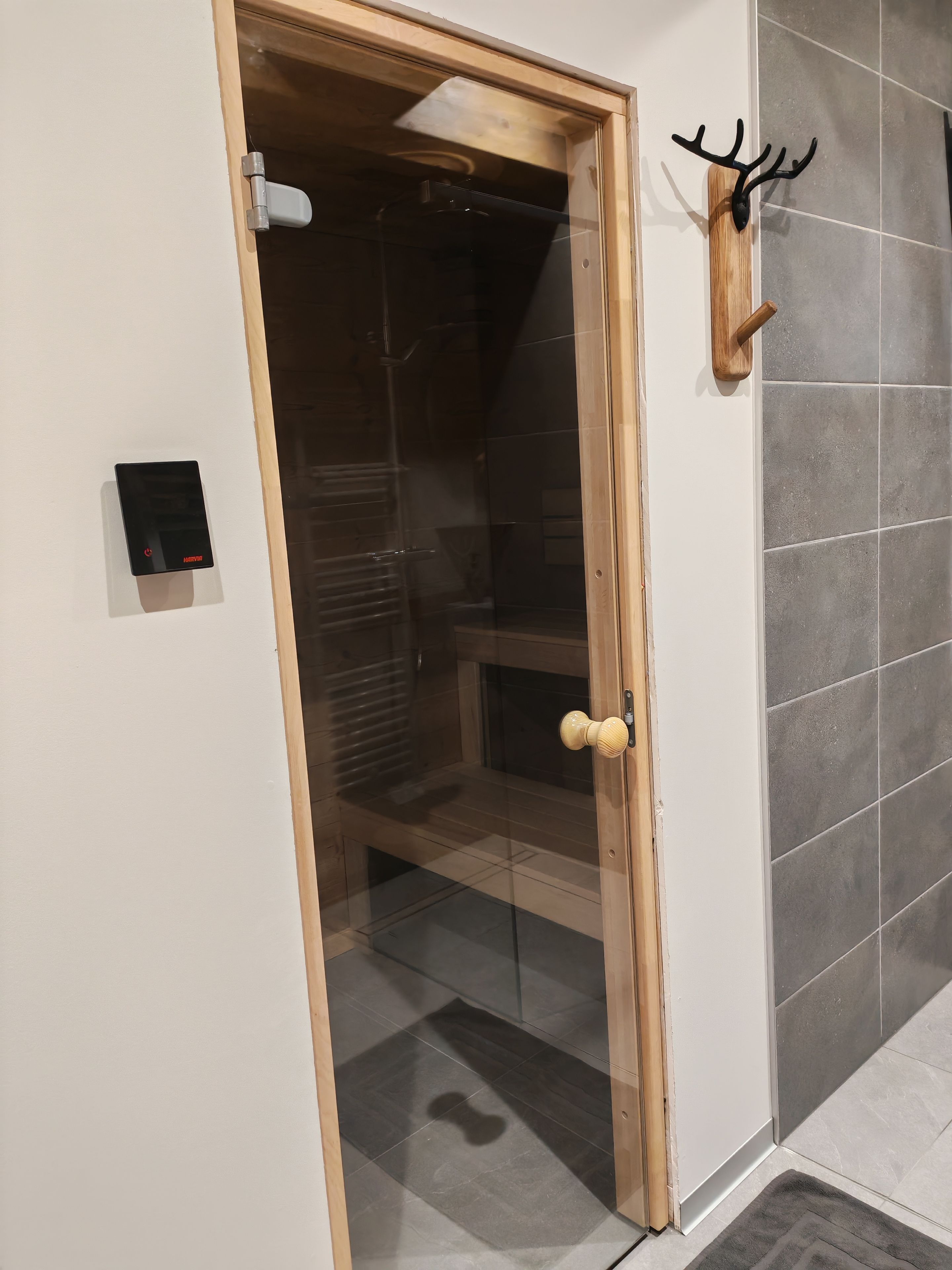 A room with a wooden door, a wall-mounted heater, and a mounted deer head.