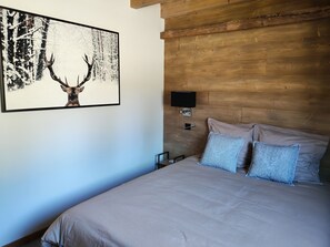 Ein Schlafzimmer mit einem Bett, zwei Kissen, einer Wandleuchte und einem Bild von einem Reh.