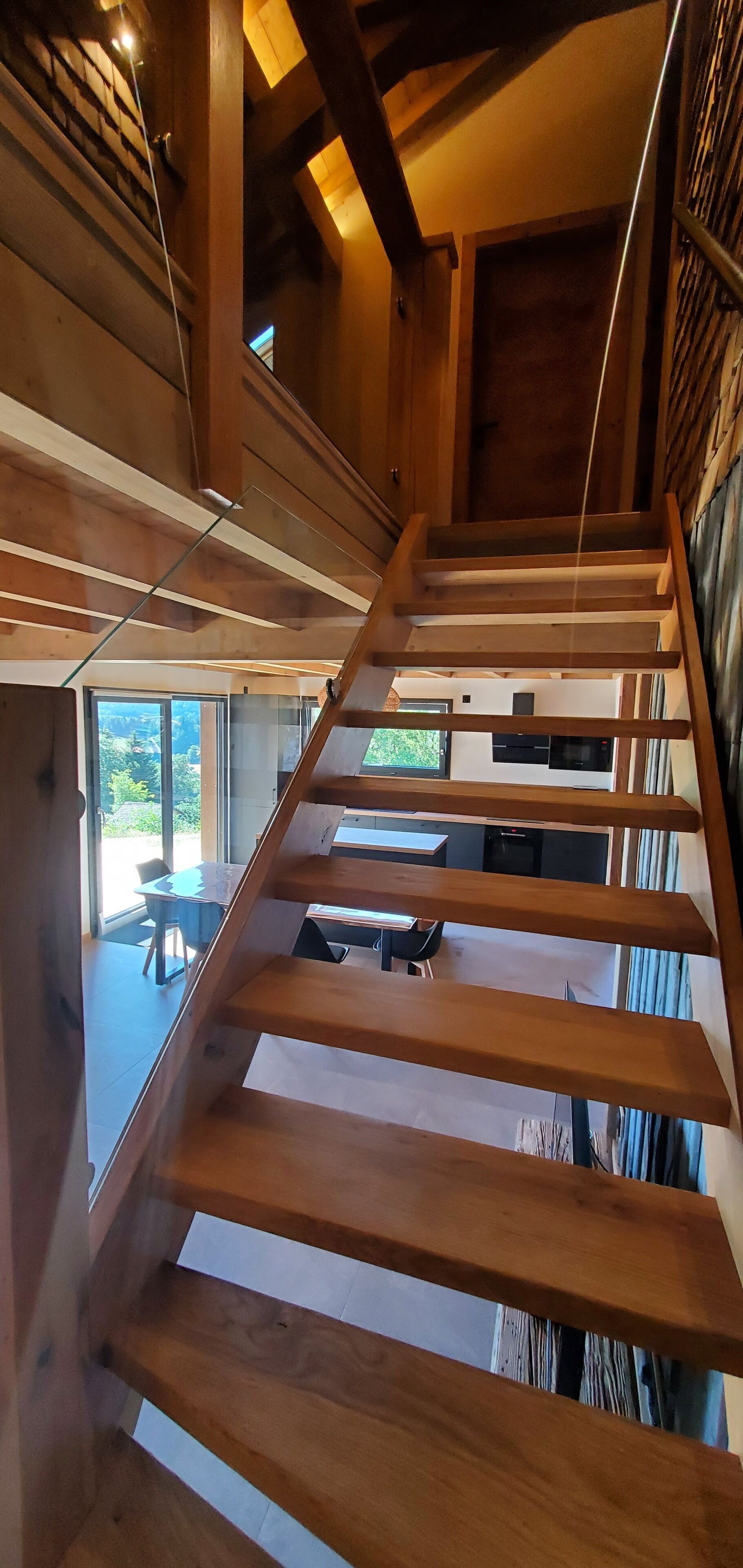 A wooden staircase with a view of a dining area and a kitchen.