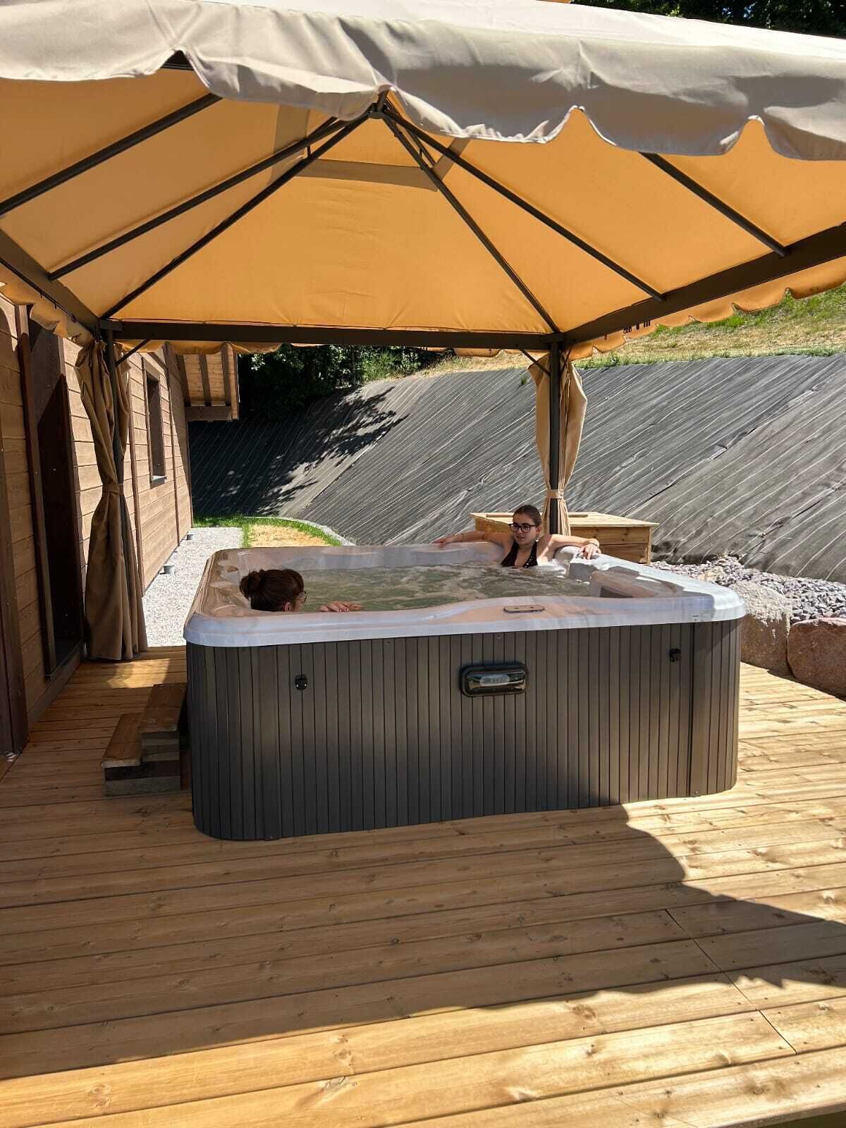 A hot tub under a canopy on a wooden deck.