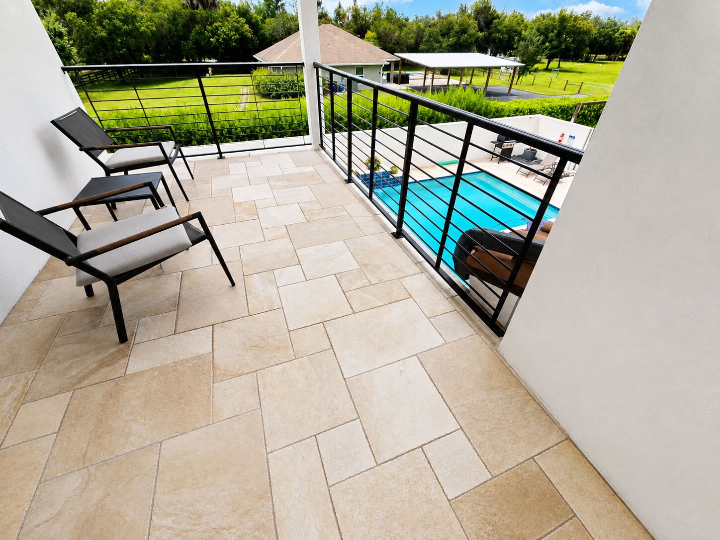 A balcony with tiled flooring, a pool, and outdoor furniture.