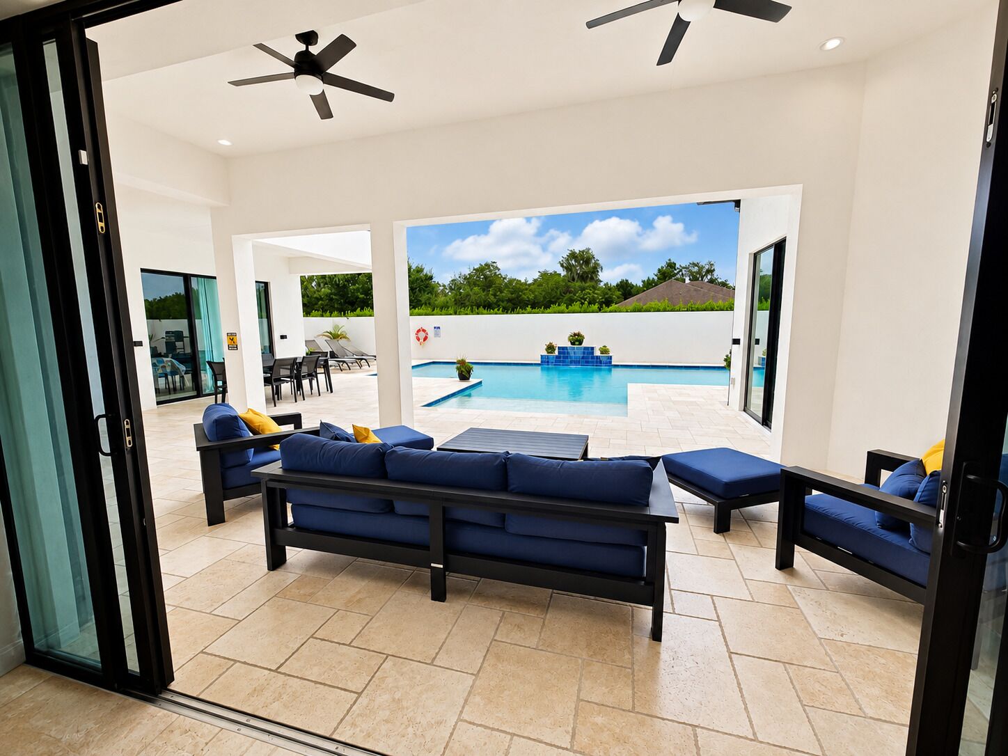 An open-plan living area with a pool, outdoor furniture, ceiling fans, and a view of the outdoors.