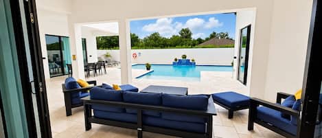 An open-plan living area with a pool, outdoor furniture, ceiling fans, and a view of the outdoors.