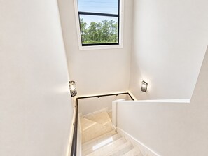 A staircase with a view of trees through a window.