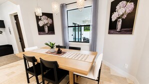 Een eetruimte met een houten tafel, zwarte stoelen, een potplant en kunst aan de wanden.