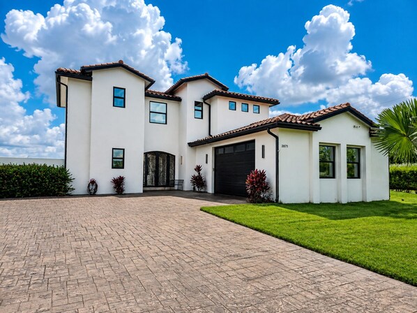 A two-story house with a driveway and a well-maintained lawn.