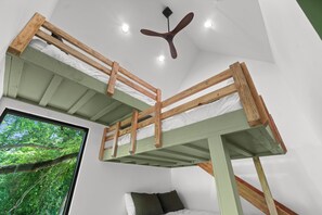 A bunk bed room with a ceiling fan, a window with a view of trees, and a bed with pillows. - Luxury Treehouse on 470 Acre Adventure on Two Rivers (Mountain View)