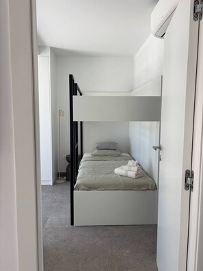 Ein Stockbett mit weißem Kopfteil, ein Nachttisch und eine Stehlampe.