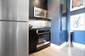 A modern kitchen with stainless steel appliances, a microwave, oven, and a trash can. - Designer 3BR • Two Levels • 2.5 BTHR (Montréal)