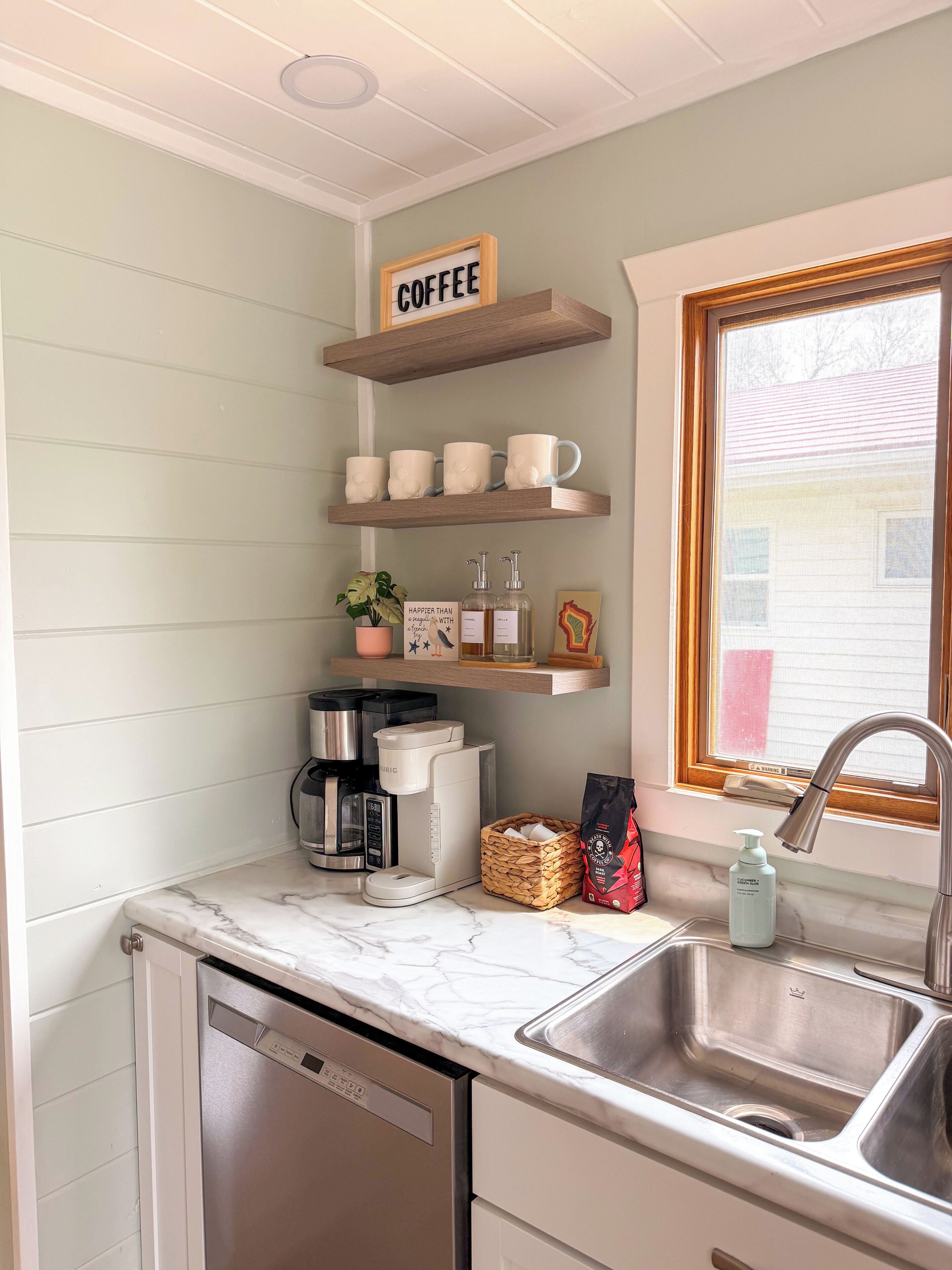 Bright kitchen coffee bar with open shelving and sunny window views