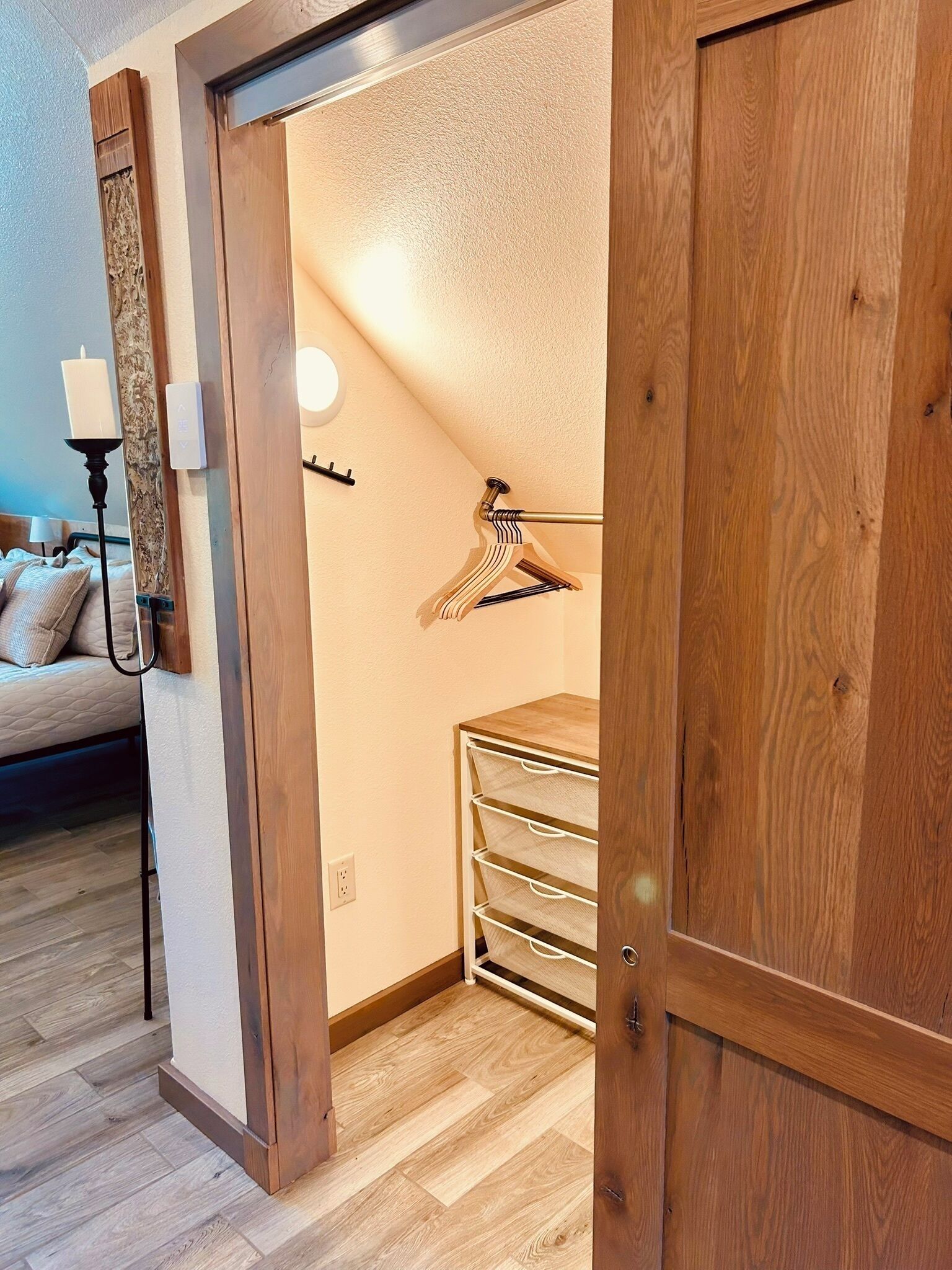 A wooden closet with a hanging rack and a light fixture.