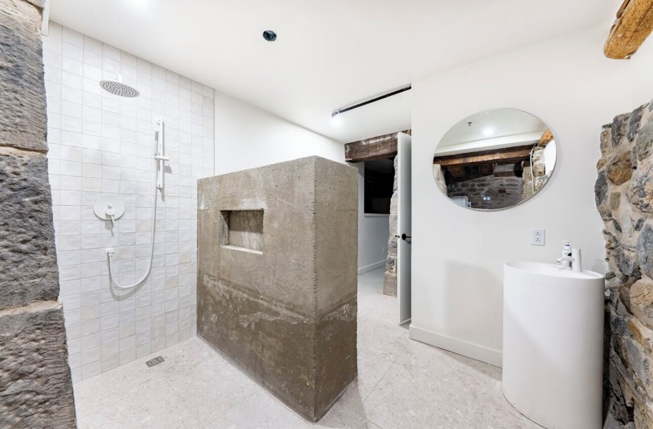 A modern bathroom with a shower, a sink, and a stone accent wall.