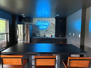 A modern kitchen with a marble backsplash, a stainless steel refrigerator, and a neon sign reading 'No Wake Zone.' - Fresh and Modern Lake House Steps to the Water! (Dry Ridge)