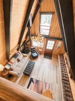 Una stanza in stile loft con divano, poltrone, camino e lampadario.