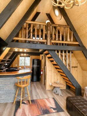 Ein rustikaler Innenraum mit einer Holztreppe, einer Küchenzeile und einer Sitzecke.