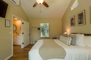Ein Schlafzimmer mit einem Bett, einem Deckenventilator, einem Fenster mit Jalousien und einer Tür zu einem Badezimmer.