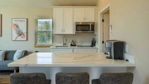 A kitchen with white cabinets, a central island, a microwave, and a toaster. - Ponerosa Nest-Quails Nest 1hr Drive to Yosemite (Mariposa County)