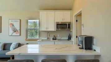 A kitchen with white cabinets, a central island, a microwave, and a toaster.