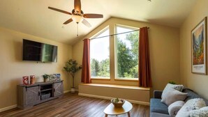 A living room with a ceiling fan, a TV, a window with curtains, a sofa, and a small table with a bowl. - Ponderosa Nest-BlueJay Nest 1hr drive to Yosemite (Mariposa County)