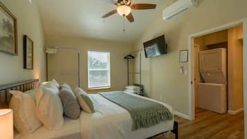 A bedroom with a bed, ceiling fan, TV, and a walk-in closet.