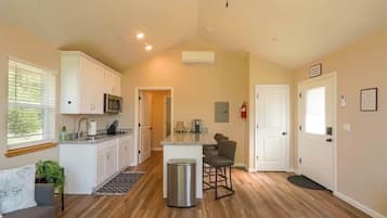 A spacious kitchen with white cabinets, a microwave, and a small island with bar stools.