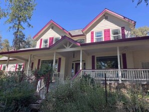 A two-story house with a porch, a staircase, and a fenced yard. - Yosemite Firehouse Inn-Cottage (Mariposa County)