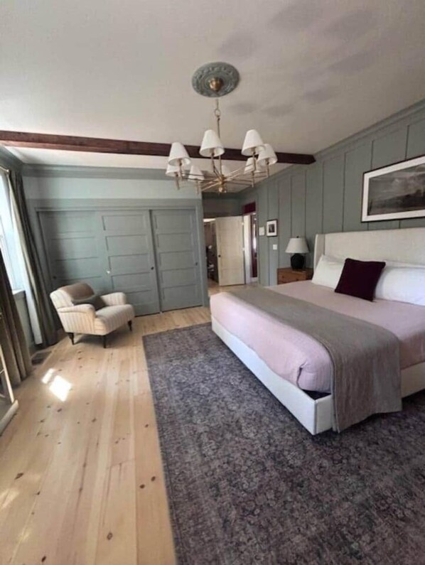 Ein Schlafzimmer mit Bett, Stuhl, Teppich und Deckenleuchte.