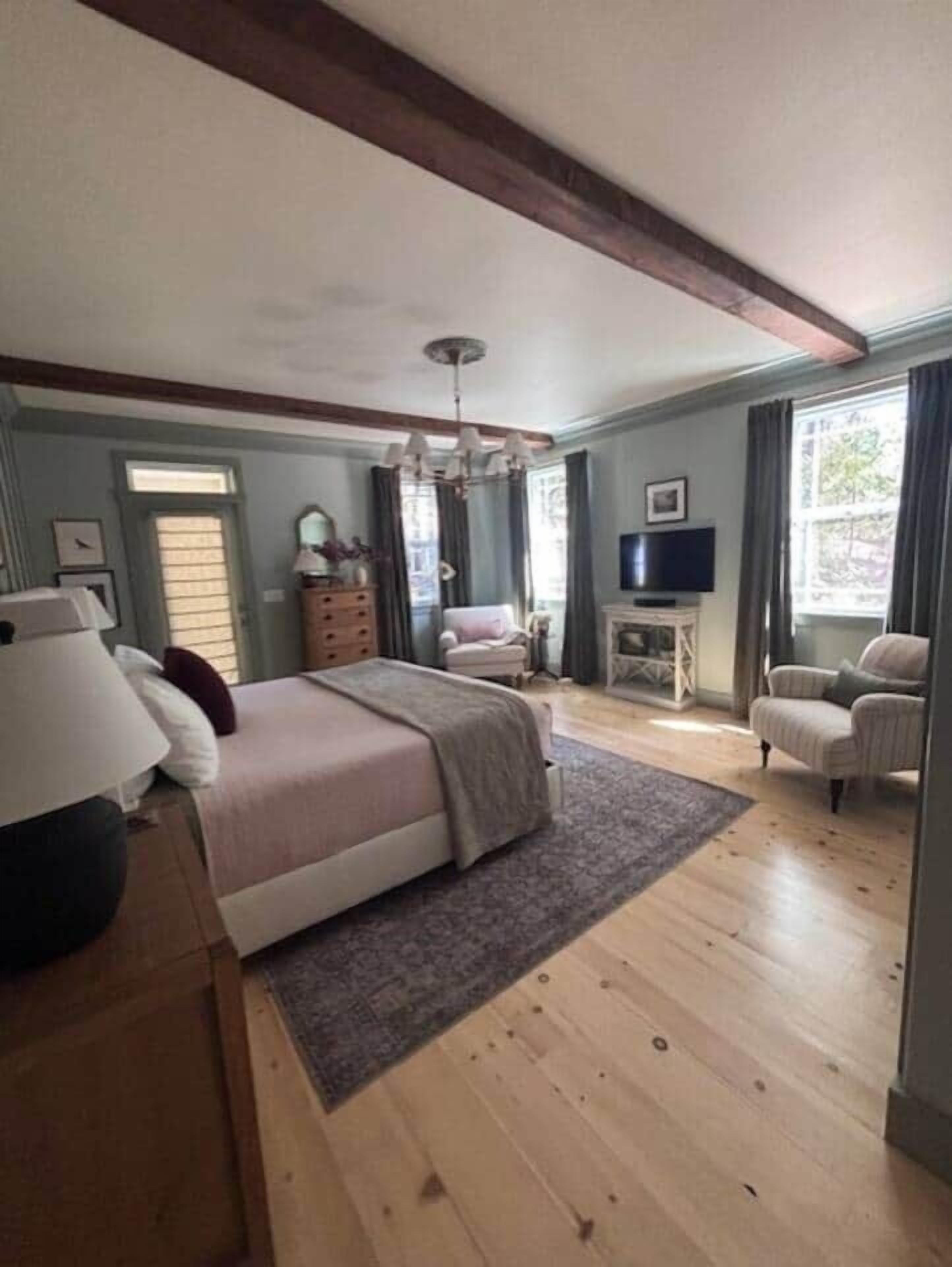 Een slaapkamer met een bed, een dressoir, een televisie en een stoel.