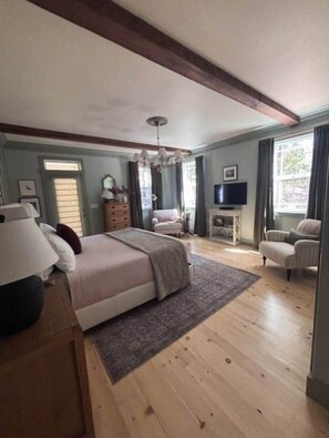 Ein Schlafzimmer mit Bett, Kommode, Fernseher und Stuhl.