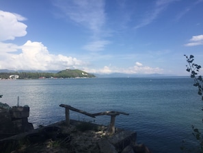A coastal landscape with a body of water, a small island with buildings, and a wooden structure on the shore. - Sunrise and Sunset in Lake Sevan (Sevan)