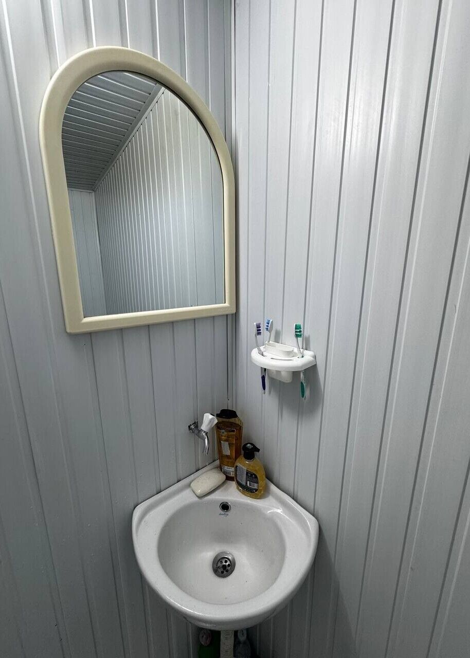 Baño con lavamanos blanco, espejo y dispensador de jabón.