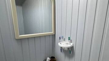 Baño con lavamanos blanco, espejo y dispensador de jabón.