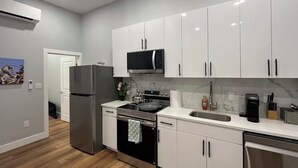 Uma cozinha moderna com armários brancos, eletrodomésticos de aço inoxidável e uma bancada de mármore.