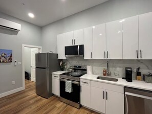 Eine moderne Küche mit weißen Schränken, Edelstahlgeräten und einer Marmor-Spritzschutzwand.