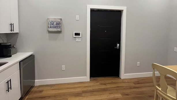 Uma cozinha moderna com armários brancos, uma porta preta e um aviso na parede.