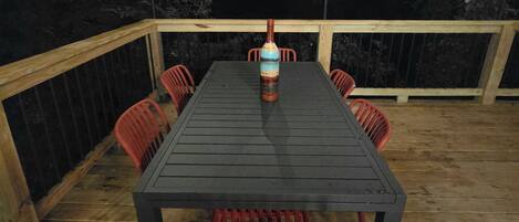 An outdoor deck with a table and chairs, surrounded by a wooden railing.