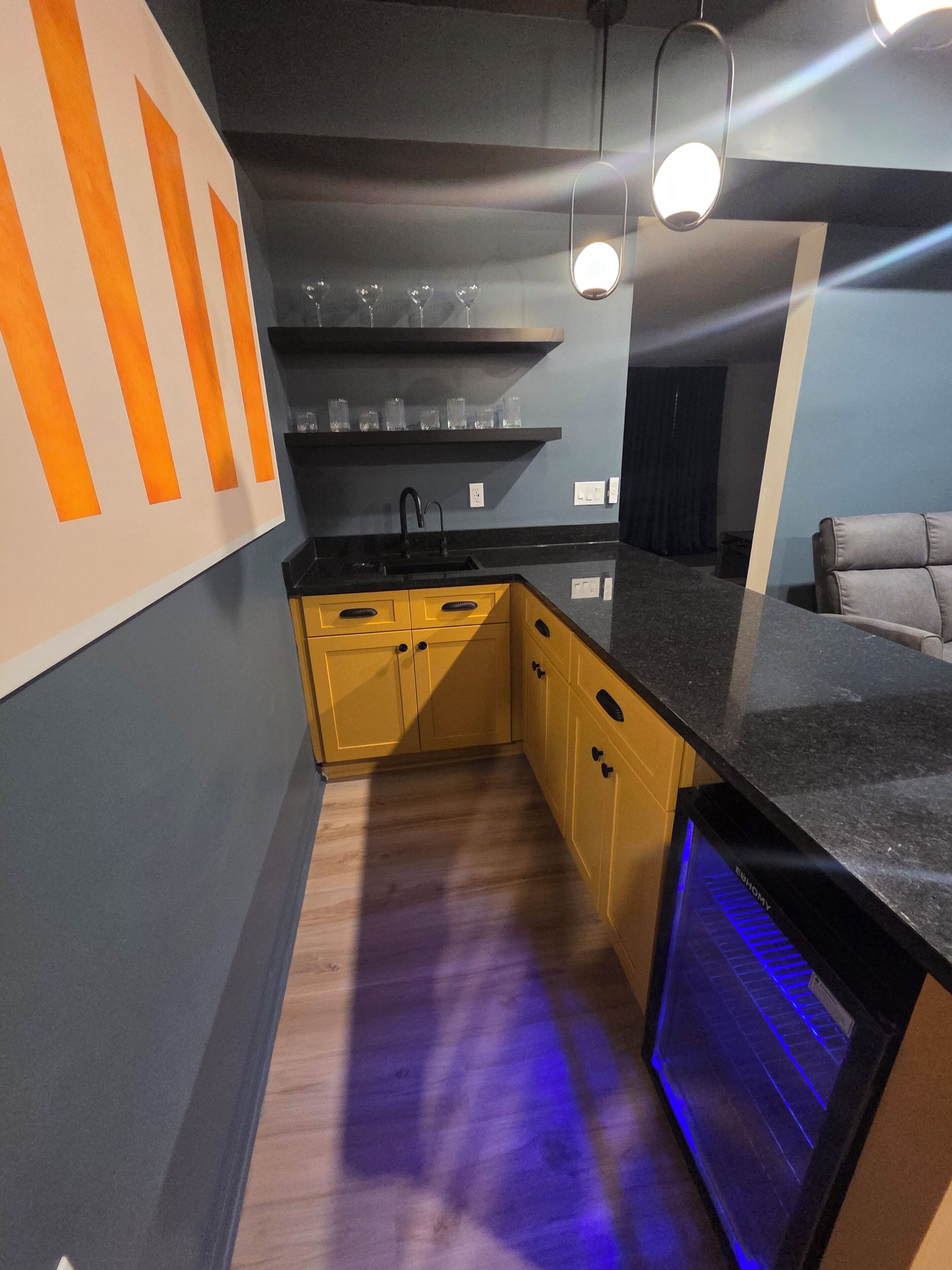 Eine moderne Küche mit gelben Schränken, einer schwarzen Arbeitsplatte und einem eingebauten Backofen.