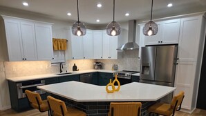 A modern kitchen with a central island, white cabinets, and a stainless steel refrigerator. - 5 Min to Downtown • Hot Tub • Game Room (Atlanta)