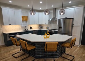 A modern kitchen with a central island, white cabinets, and a stainless steel refrigerator. - 5 Min to Downtown • Hot Tub • Game Room (Atlanta)