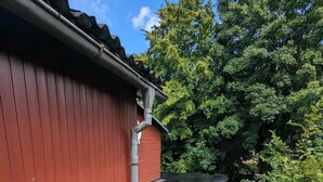 A red building with a sloped roof, a stone pathway, and a garden with pink flowers and green foliage. - Gemütliche & familienfreundliche Ferienwohnung von HerzZeit- Harz in Wernigerode (Wernigerode)