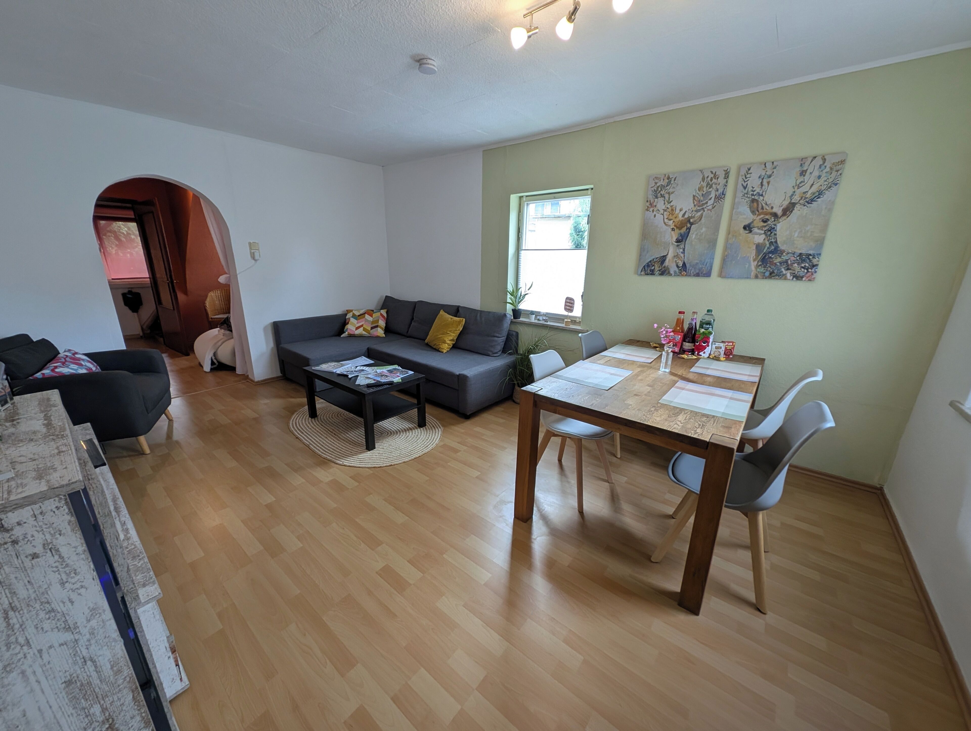 Un salon moderne avec un canapé gris, une table basse et une table à manger avec des chaises.