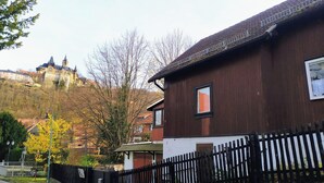 A residential building with a wooden facade, a black metal fence, and a stone wall. - Gemütliche & familienfreundliche Ferienwohnung von HerzZeit- Harz in Wernigerode (Wernigerode)