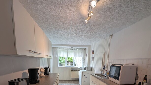 A modern kitchen with white cabinets, a wooden countertop, a toaster, a kettle, a microwave, and an oven. - Gemütliche & familienfreundliche Ferienwohnung von HerzZeit- Harz in Wernigerode (Wernigerode)