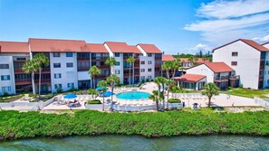 Ein Hotel mit mehreren Gebäuden, einem Schwimmbad und Blick auf das Wasser.