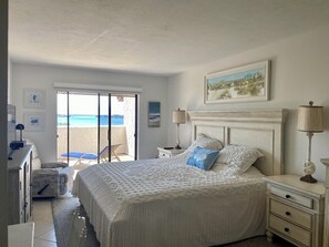 A bedroom with a large bed, a desk, a chair, and a view of the beach through a glass door. - Beautiful Condo with Amazing Views, short walk to Siesta Key Beach! Stores close (Sarasota)
