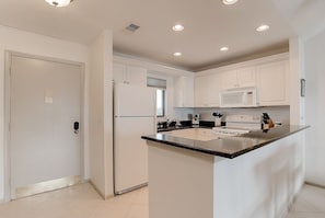A modern kitchen with white cabinetry, a central island, and built-in appliances. - Beautiful Condo with Amazing Views, short walk to Siesta Key Beach! Stores close (Sarasota)