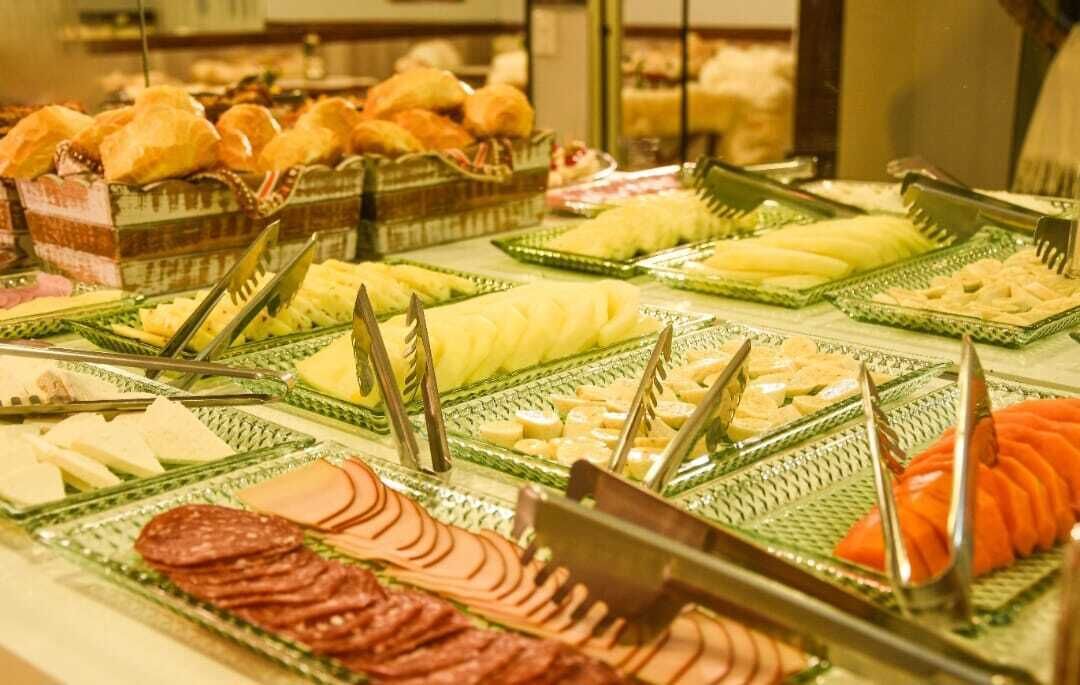 A buffet with various food items including meats, cheeses, and fruits.