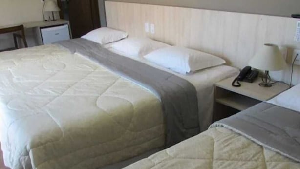 A hotel room with two beds, a bedside table with a lamp, and a phone. - Villa di Cavi (Gramado)
